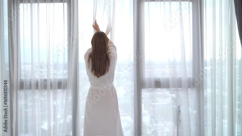 A young woman in red lingerie wakes up from a rest and relaxes by the window, healthy lifestyle and morning routine