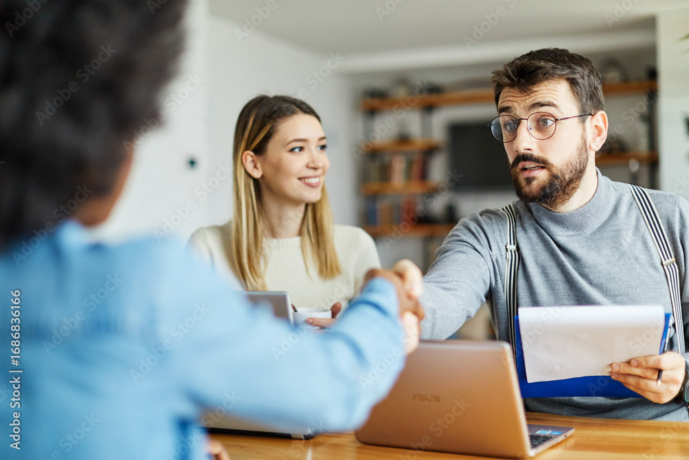 Obraz premium Young happy couple and a real estate agent in the office. Management members and a candidate at a job interview. Businesspeople concept