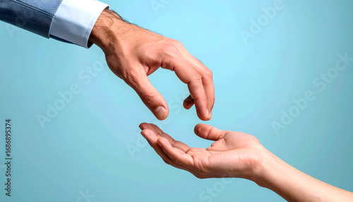 A man's hand in a suit reaches down towards an open, receiving hand against a light blue background, suggesting offering or assistance.