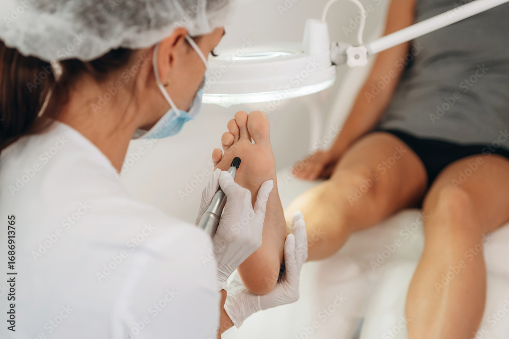 Naklejka premium Visitor is sitting, feet getting peeled. Podiatrist with client in clinic