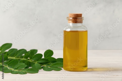 Golden oil bottle showcases vibrant moringa leaves, highlighting
