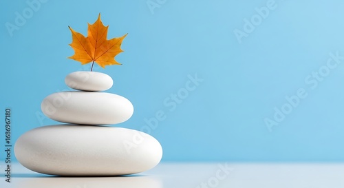 Zen Stones and Autumn Leaf Balance Against a Blue Background