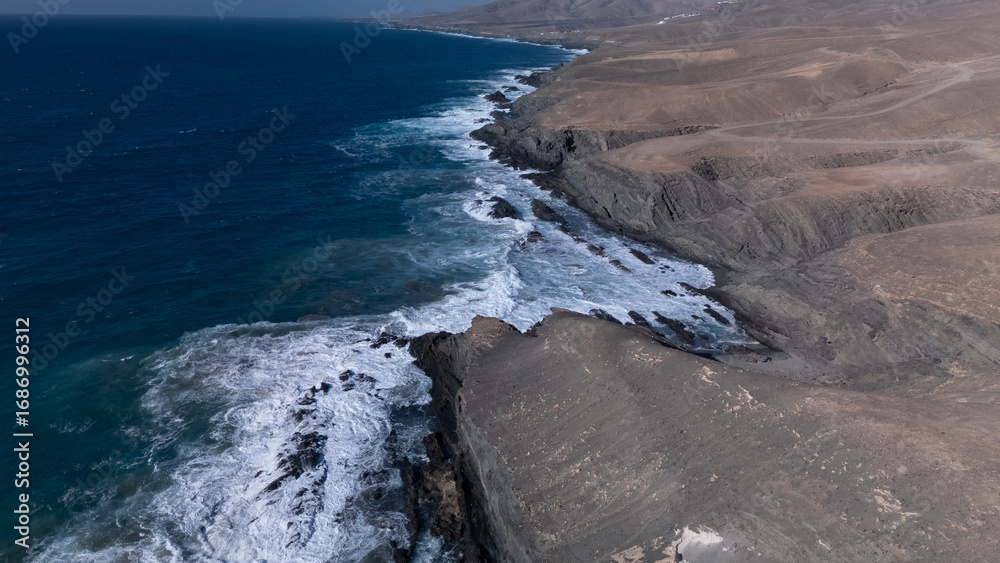 Fototapeta premium This is a high-angle aerial view of a coastline, showing the striking contrast between the ocean and the land.