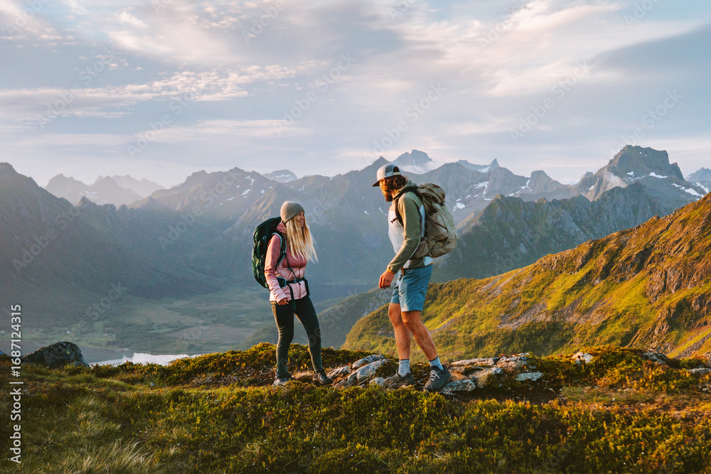 Obraz premium Friends couple hiking in Norway man and woman travel outdoor active vacations healthy lifestyle romantic tour, family mountaineering in Lofoten islands adventure trip boyfriend and girlfriend tourists
