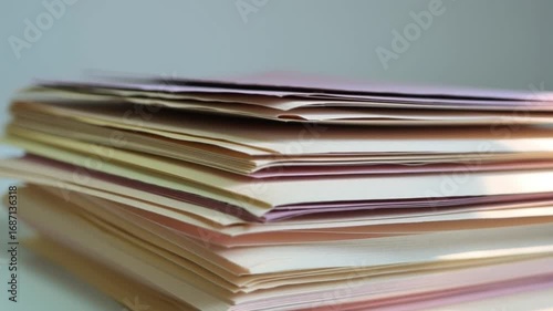Neatly Organized Stack of Colorful Pastel Paper Folders Stationery in Sunlit Office with Soft Shadows and Warm Hues