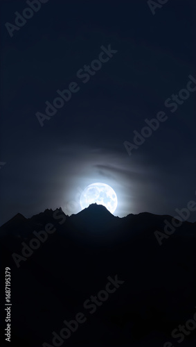 Full moon rising behind silhouetted mountain range at night dark