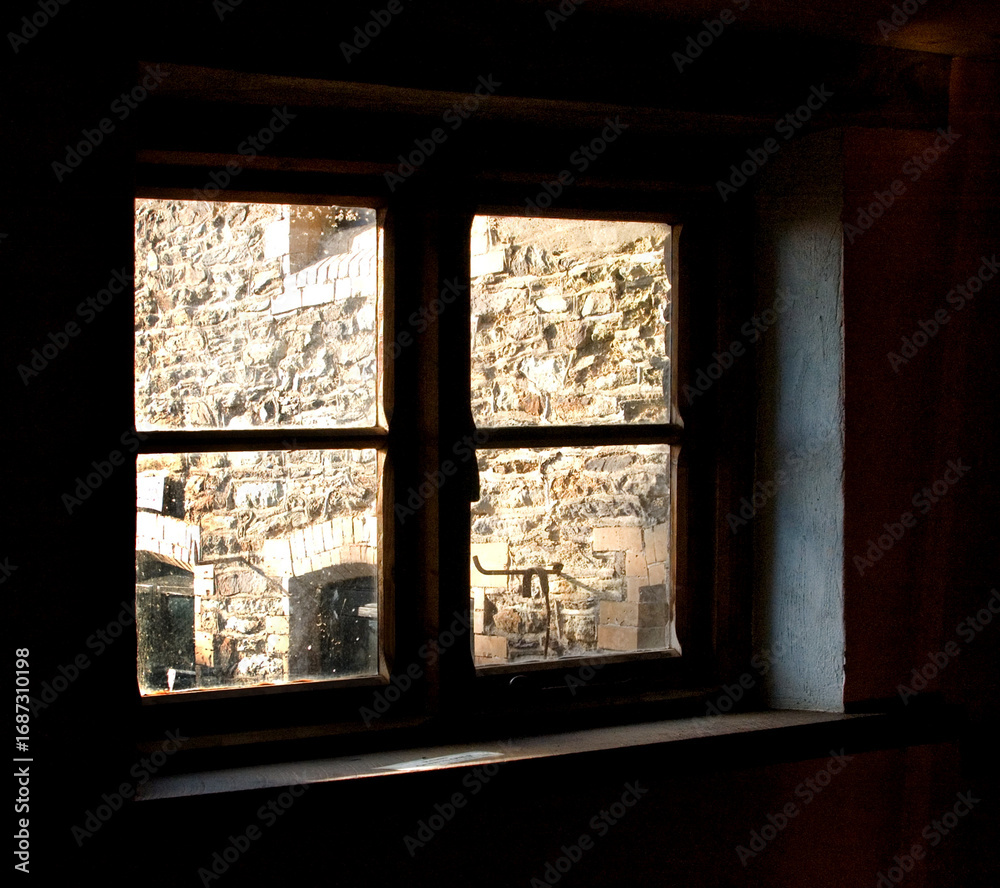 Fototapeta premium A window with a view of a stone wall.