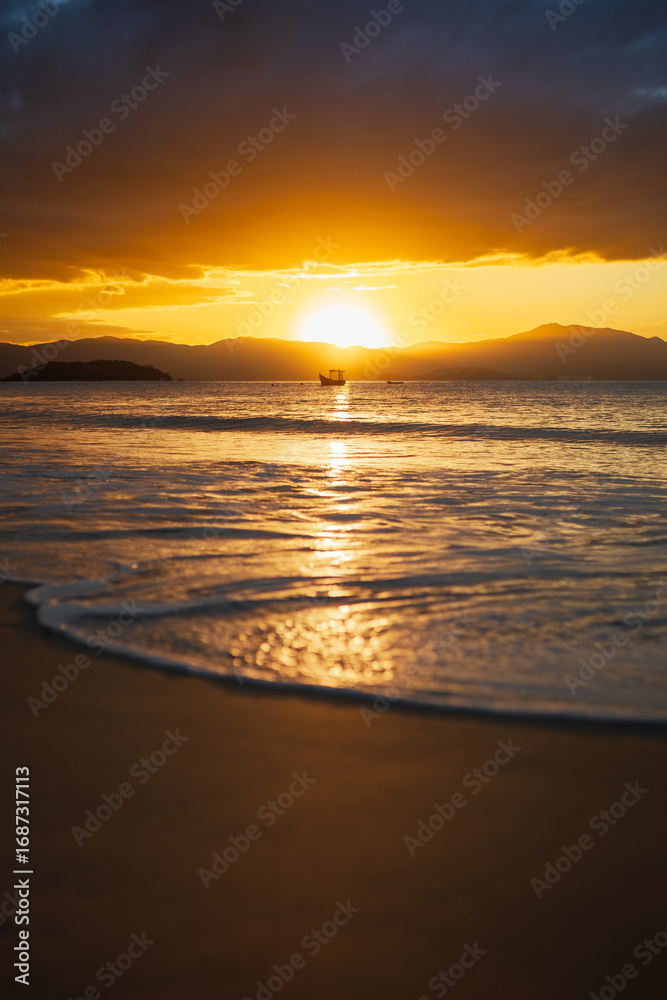 Fototapeta premium Golden sunset over the ocean with fishing boat and mountains