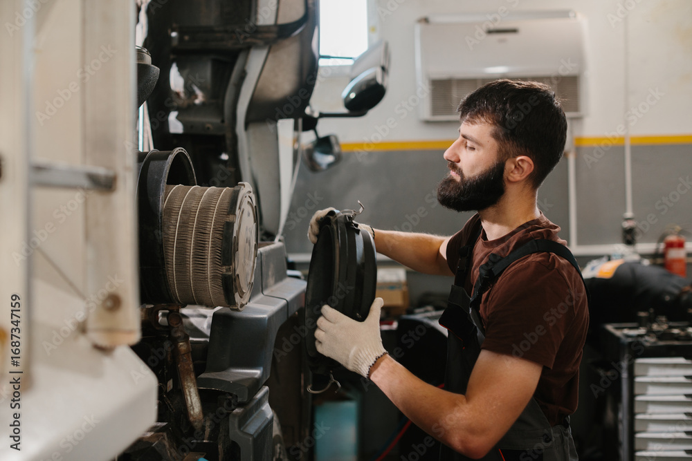 Fototapeta premium Mechanic replacing air filter in a truck engine during maintenance