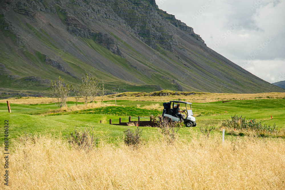 Naklejka premium Golf course in stunning Icelandic landscape with rocky mountains and rolling green fields