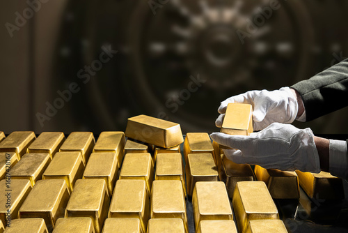 Papier peint Banker's hands in white gloves, bank vault manager holding a gold bar, national gold reserv holdings concept
