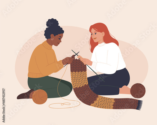 Two diverse friends enjoying their knitting hobby, collaborating on a handmade striped scarf project