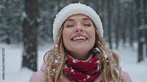 Young woman wearing winter clothes enjoying snowfall in a forest