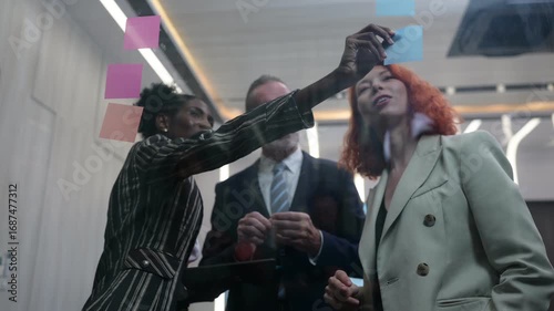 Diverse business team brainstorming with sticky notes in modern office, discussing strategy, innovation, and teamwork collaboration for project planning and creative business solutions.