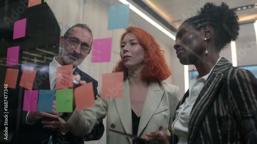 Diverse business team brainstorming with sticky notes in modern office, discussing strategy, innovation, and teamwork collaboration for project planning and creative business solutions.