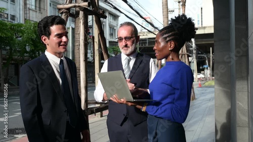 Business professionals having outdoor meeting on city street, discussing project with laptop, symbolizing teamwork, communication, leadership, consulting, and modern corporate strategy.