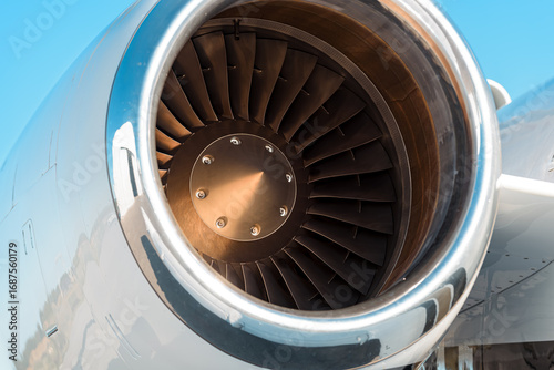 Obraz na plátně Tight close-up of a polished aircraft jet engine intake, the engine is mounted on the right side of the aircraft and the image highlights the turbofan details including blades, nose cone and hardware