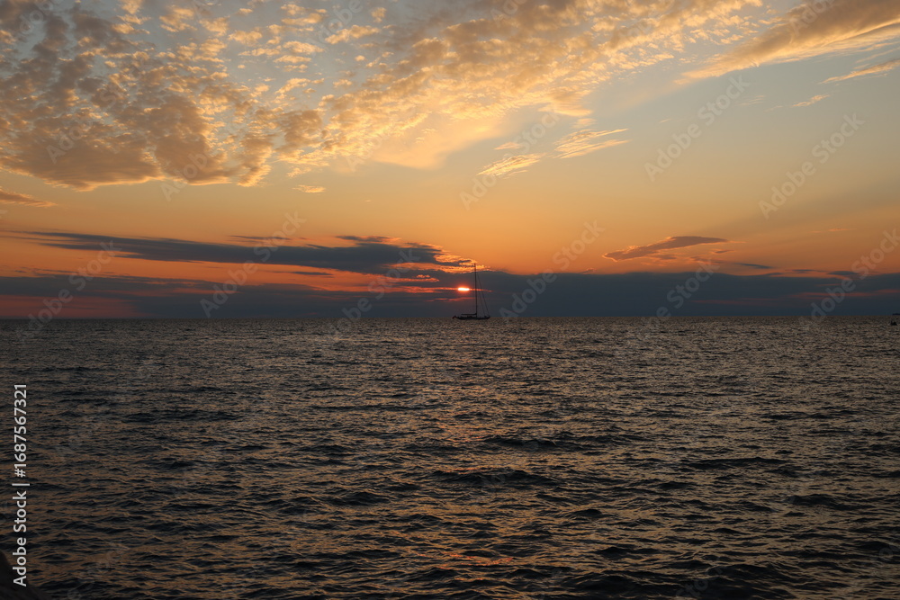 Naklejka premium Schiff in der Ferne im Sonnenuntergang über der slowenischen Adria