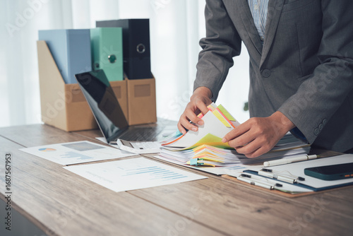 Organized Workflow: A focused professional meticulously manages an array of documents within a modern office setting. The image evokes a sense of efficiency, precision.
