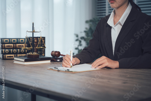 Focused Counsel: A professional individual meticulously pens important documents at a desk, the tools of their trade - a gavel, scales of justice.