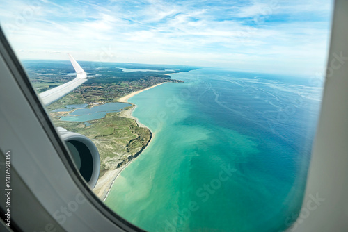 Beautiful ocean view from an airplane window.
Colorful blue shades of the sea gazed through a jet plane.
