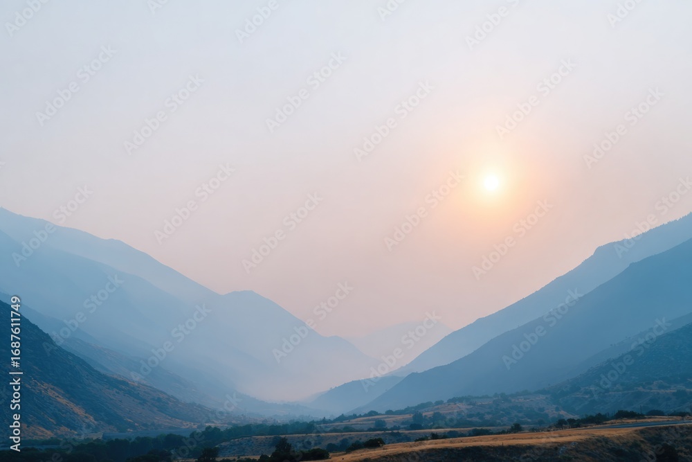 Naklejka premium Calm landscape features soft blue mountains under hazy sunset gl