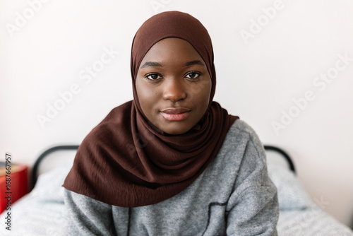 Portrait of young serious african woman in muslim headscarf at home. Proud of religion and islamic people concept