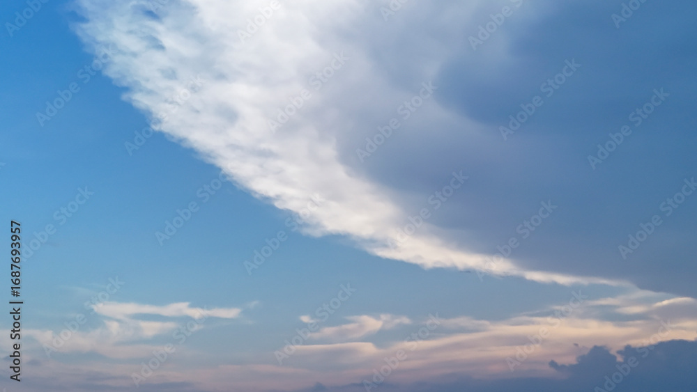 Fototapeta premium Vibrant sky features dramatic clouds contrasting with a clear blue backdrop, capturing the beauty of nature during the transition from day to evening.