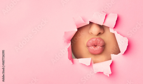 Canvas Print Woman pouting plump bright lips, peep into the slit of pink paper, free space