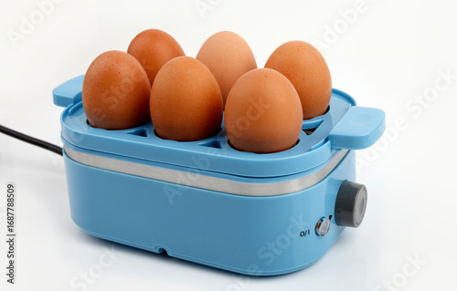 Blue egg cooker steaming six brown eggs on white background