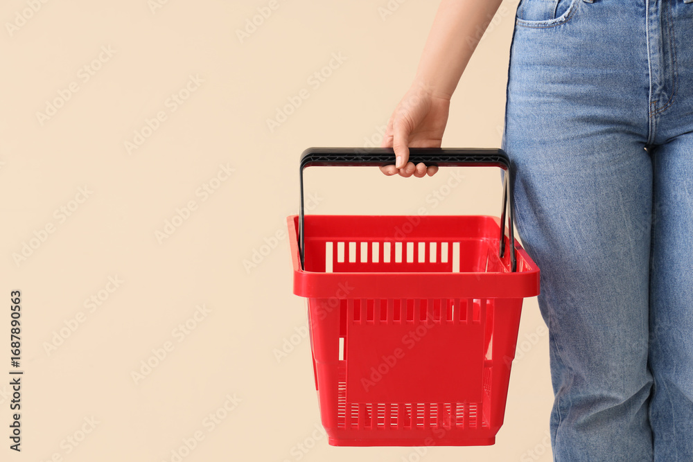Fototapeta premium Woman with red shopping basket on beige background