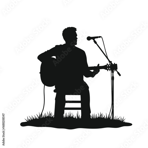 Silhouette of man playing acoustic guitar and singing into microphone