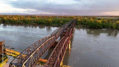 Foto Metal viaduct spanning Po River near Cremona, Italy, with golden sunset illumina
