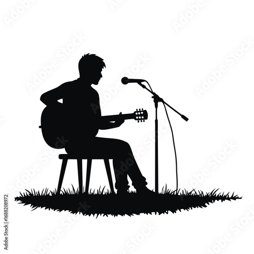 Silhouette of man playing acoustic guitar on stool with microphone