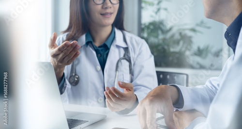 Asian medical doctor colleague working together on patient illness information. Two doctor working on laptop computer and have a discussion at doctor office in hospital or medical clinic