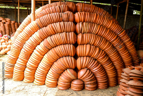 Rows of neatly arranged terracotta pots forming an intriguing pattern outdoors, showcasing craftsmanship and utility in traditional pottery. Perfect for cultural, artisan crafts, or heritage themes.
