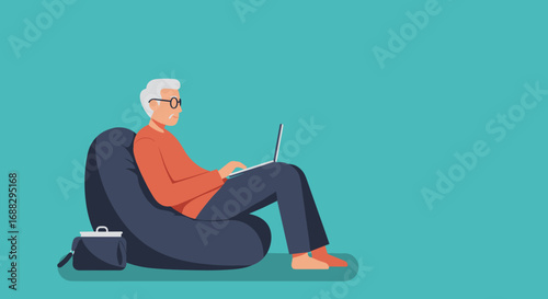 Elderly man with glasses comfortably working on a laptop from home on a beanbag chair, showcasing modern senior lifestyle and digital connectivity.