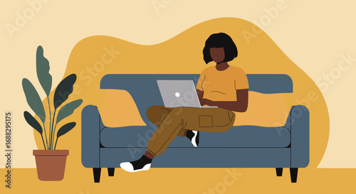 A focused woman works on her laptop while comfortably sitting on a sofa at home. Ideal for themes of remote work, digital lifestyle, online learning, and productivity.