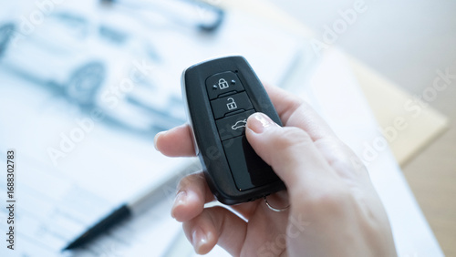 Wallpaper Mural Hand holding a car remote key with blurred background documents representing auto sales contract signing and ownership transfer Torontodigital.ca