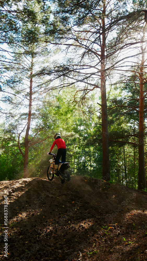 Obraz premium A enduro man ride a dirt bike in a forest, from the back