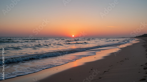Wallpaper Mural a serene beach at sunset with gentle waves lapping at the shore, the sky painted in warm hues of orange and pink, evoking a sense of calm and tranquility Torontodigital.ca