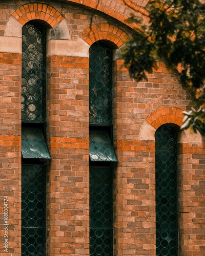 A rustic old brick building with weathered arched walls and vintage windows, showcasing architectural decay and historic charm in natural light.