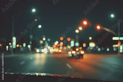 Blurry nighttime street scene with car lights creating bokeh, evoking motion and city ambience. Suggests a car ride at night