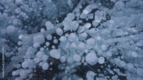 Macro diving into frozen heart of Lake Baikal ice. Capturing unique trapped bubbles, shimmering rainbows, and abstract natural wonder. Siberia's winter tourist attraction, close-up details. North 4k
