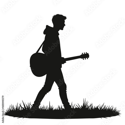Silhouette of a young man walking with an acoustic guitar