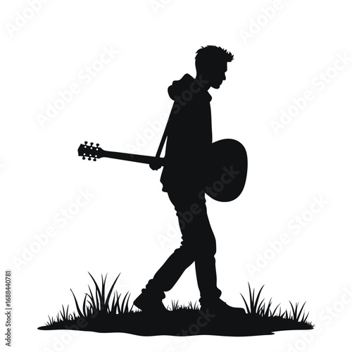 Silhouette of a young man walking with an acoustic guitar