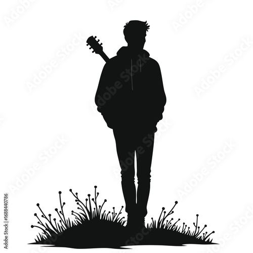 Silhouette of a young man with guitar in grass acoustic guitar