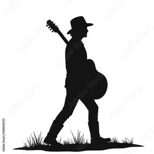 Silhouette of man in cowboy hat carrying guitar walking through grass