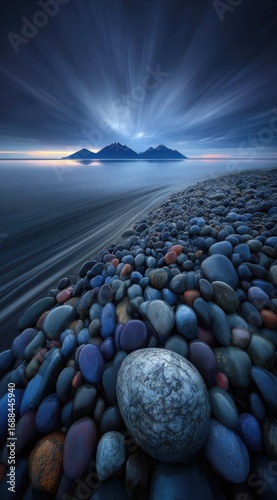 Rocky beach scene with a large egg-shaped stone, moving water, distant mountains, and a dramatic cloudscape with radial blur