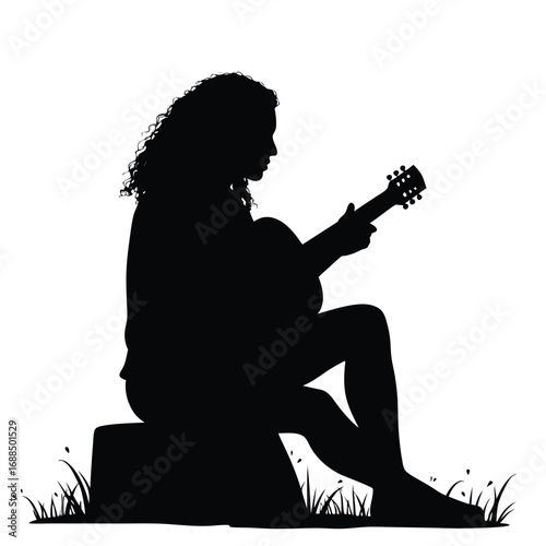 Silhouette of woman playing acoustic guitar outdoors